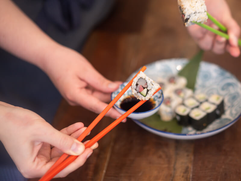 A closeup of someone holding sushi with chopsticks